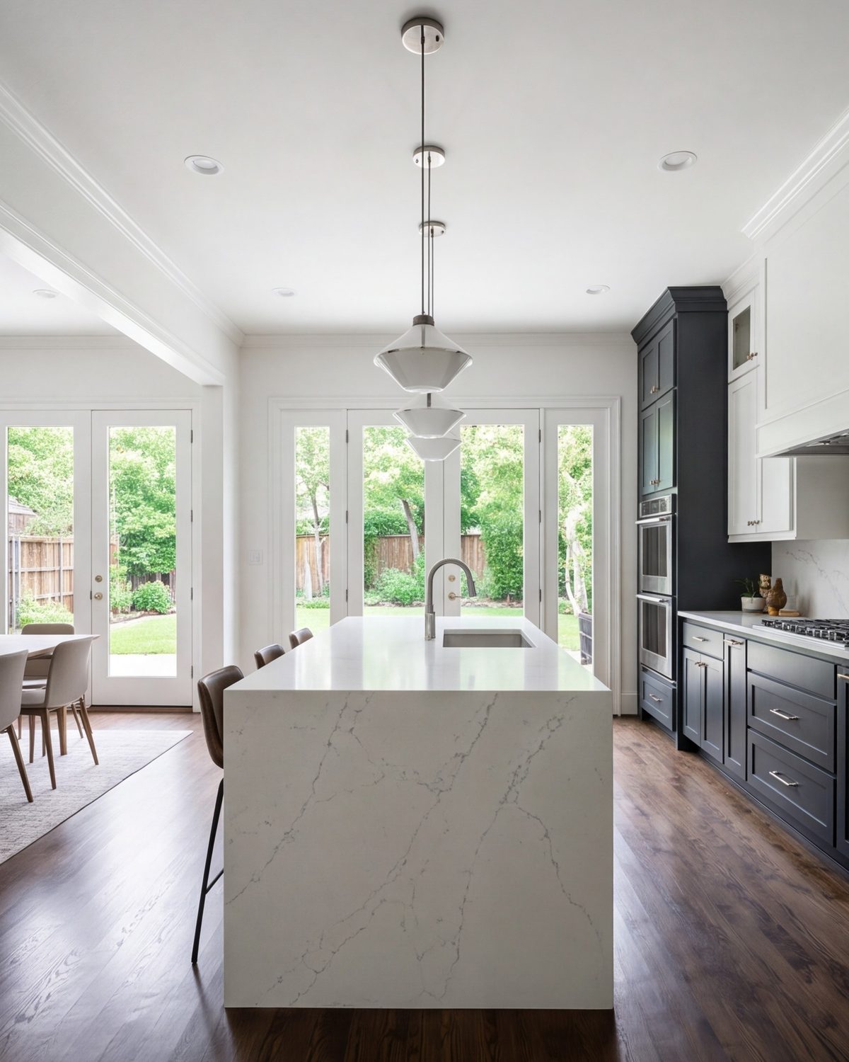 Finished kitchen seen from the dining room, with an island and pendant lights